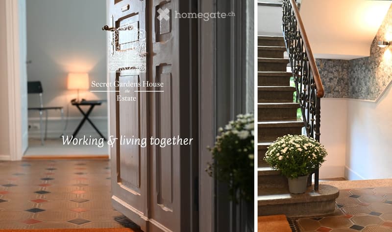 Entrance hallway with a wooden door, patterned tile floor, small table, and lamp. Staircase with metal railing and potted plant on landing.