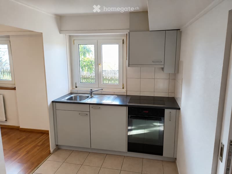Modern kitchen with white cabinets, stainless steel sink, built-in oven, and tiled countertops.