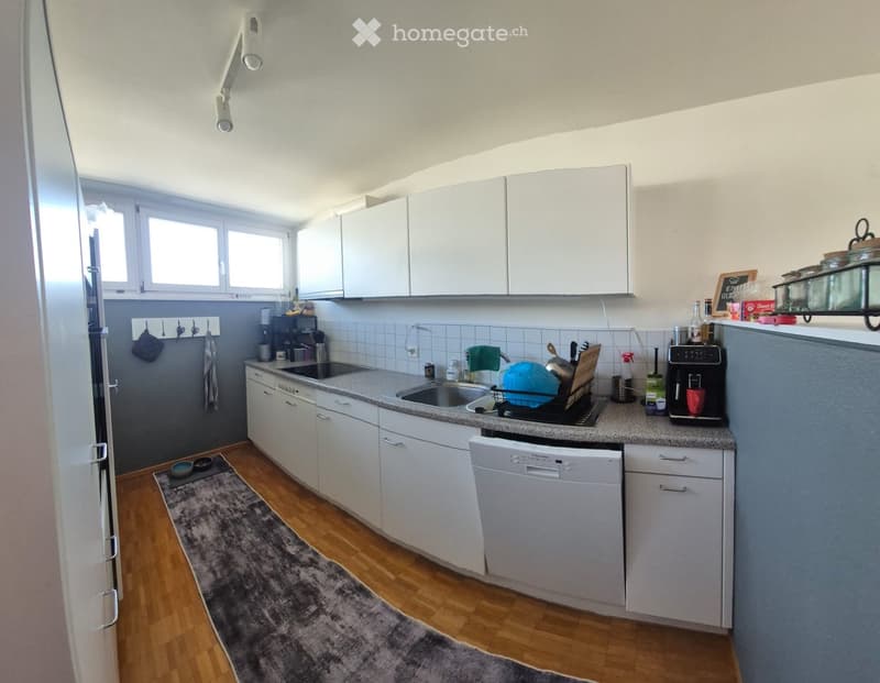 Modern kitchen with white cabinets, granite countertop, stainless steel appliances, and wooden flooring.