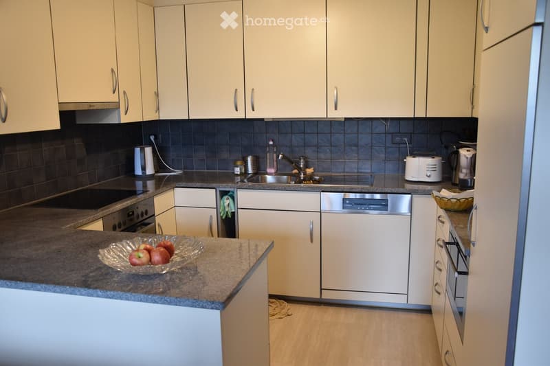 Modern kitchen with light-colored cabinets, granite countertops, and stainless steel appliances including a dishwasher, oven, and sink.