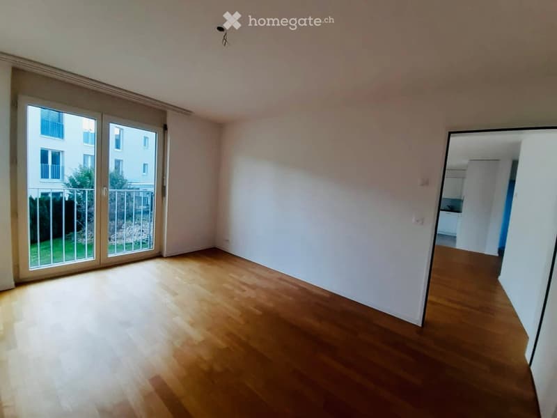 Empty room with wooden flooring, white walls, and large sliding glass doors leading to a balcony.