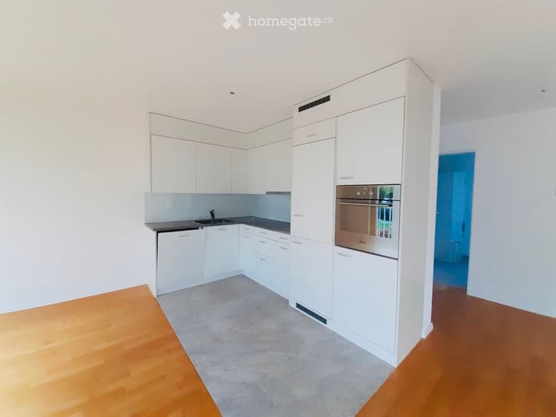 Modern kitchen with white cabinets, stainless steel oven, and a black countertop.