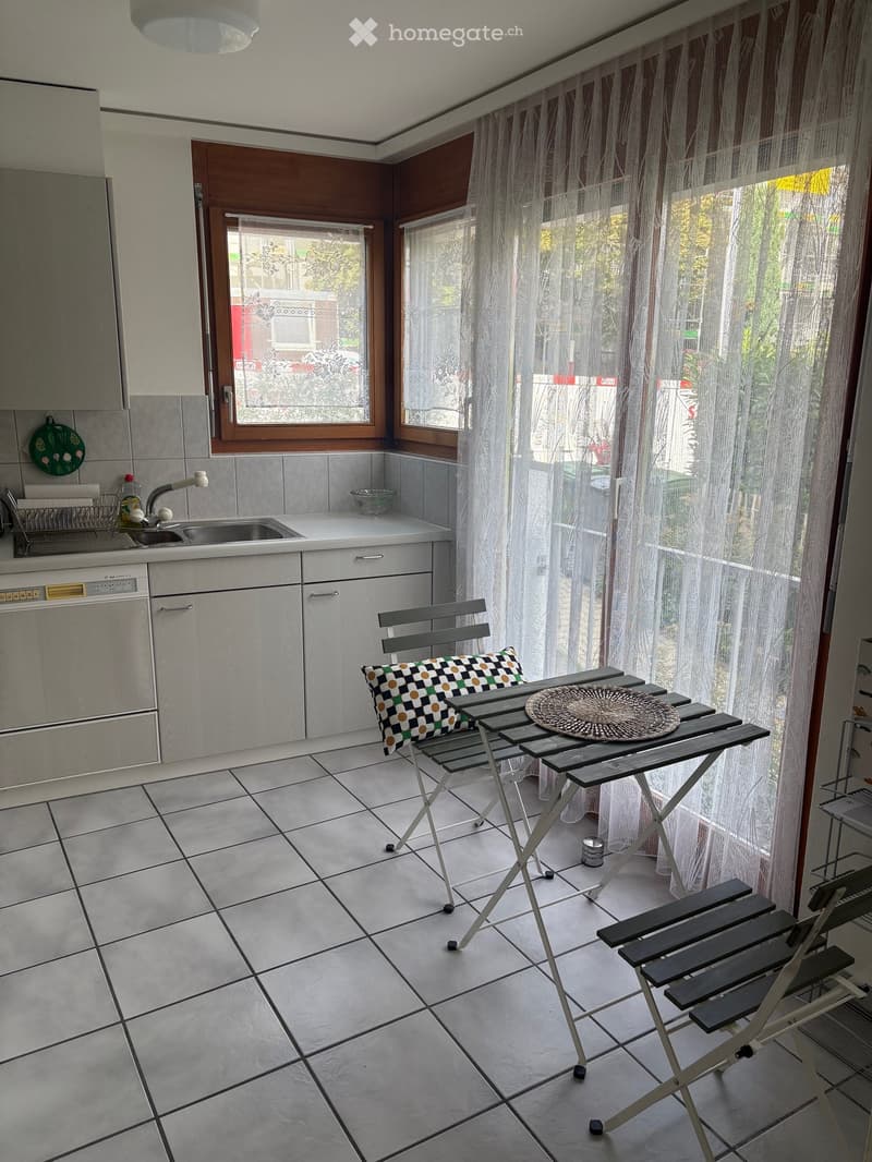 Balcony with tiled floor, white cabinets, sink, dishwasher, and a small table with chairs.