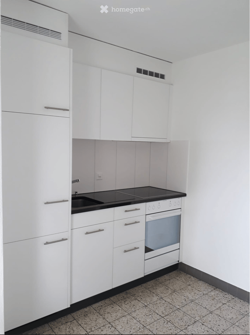 Modern kitchen with white cabinets, black countertop, sink, stove, and oven.