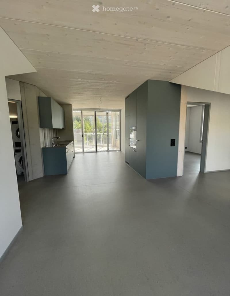 Empty room with grey cabinets, a washing machine, and a sliding glass door leading to a balcony.