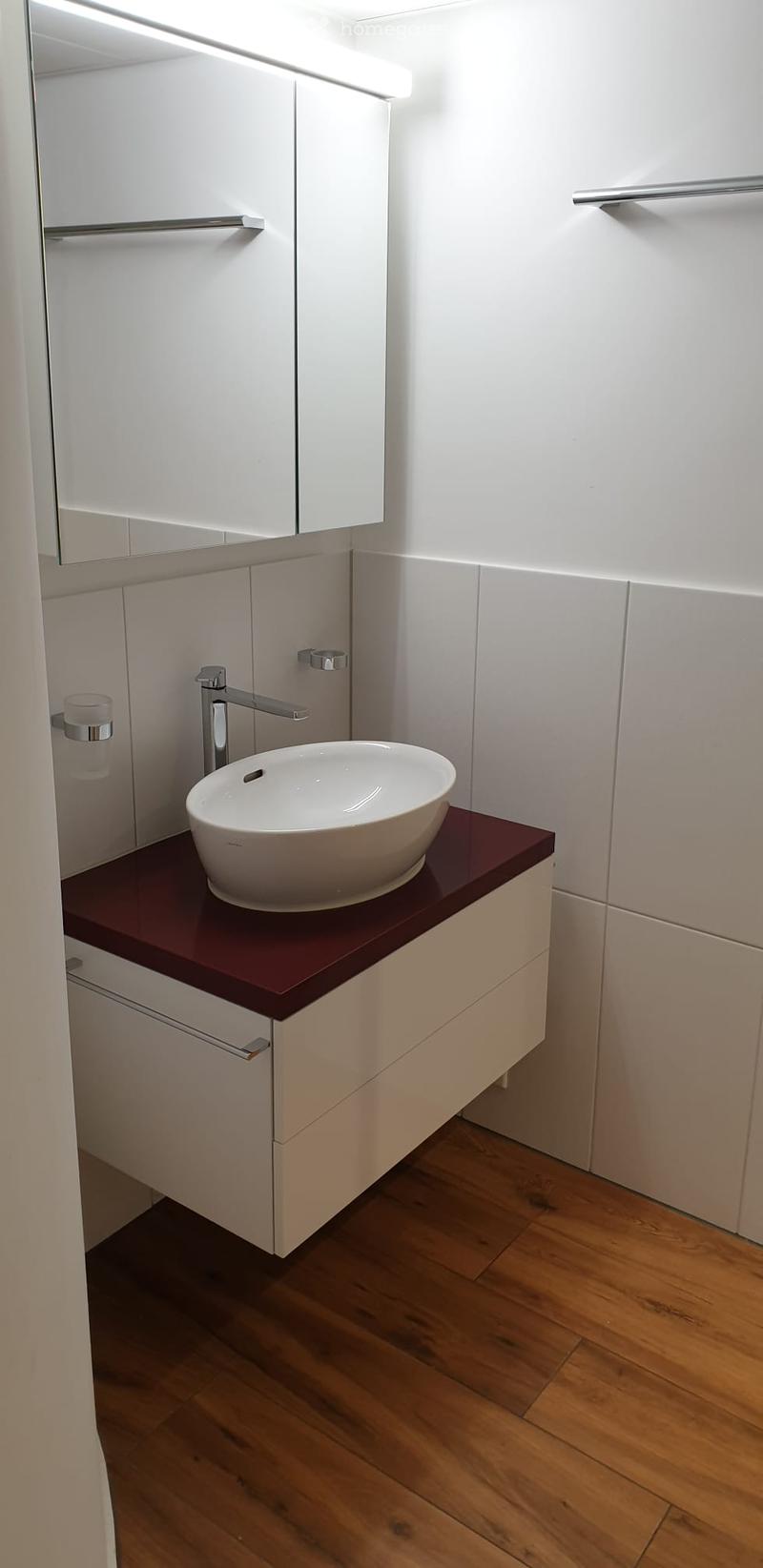 Modern bathroom with a white sink, chrome faucet, built-in cabinet, and a large mirror above the sink.
