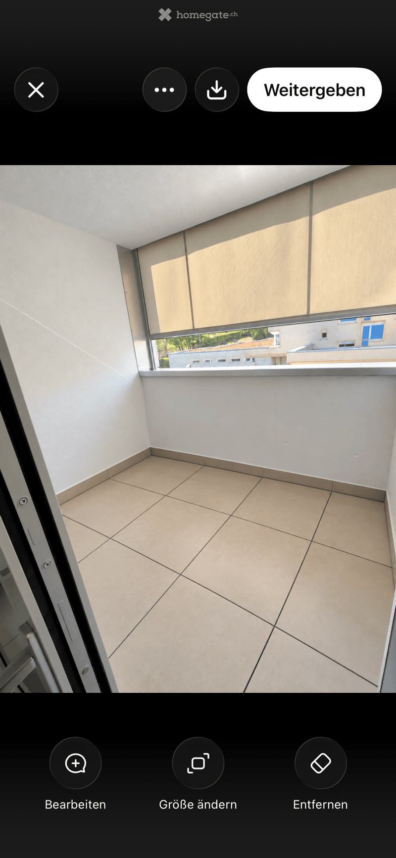 Empty room with tiled floor and large window offering a view of the outside. No furniture or equipment present.
