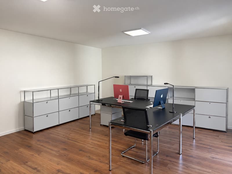 Modern office space with a sleek black desk, ergonomic chair, dual computer monitors, and built-in storage cabinets.