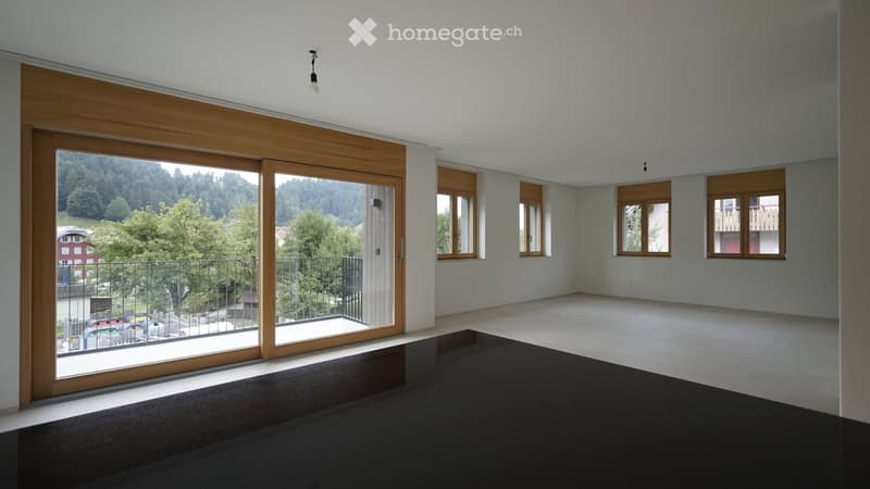 Empty room with large sliding glass doors leading to a balcony, wooden trim, and a scenic mountain view outside.