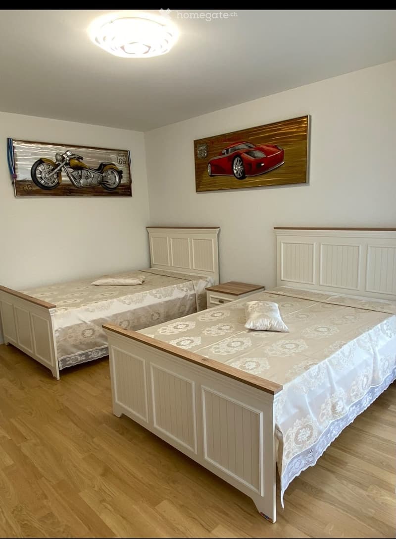 Cozy bedroom with two single beds, wooden nightstand, and decorative artwork on the walls.
