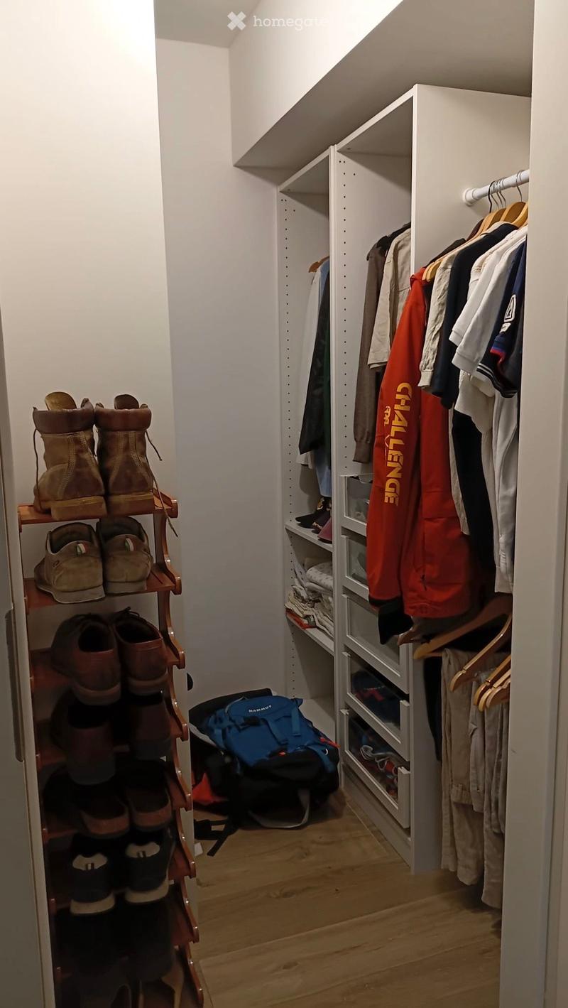 Well-organized closet with a built-in wardrobe, shoe rack, and a backpack on the floor.