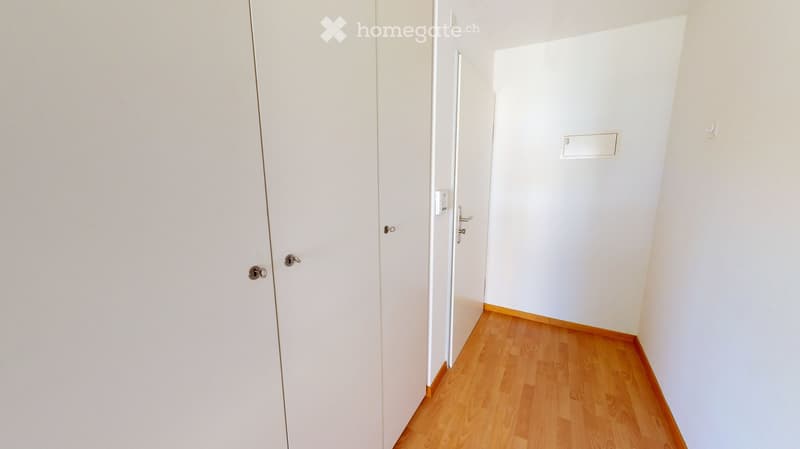 Empty hallway with white walls, wooden flooring, and two closed doors.