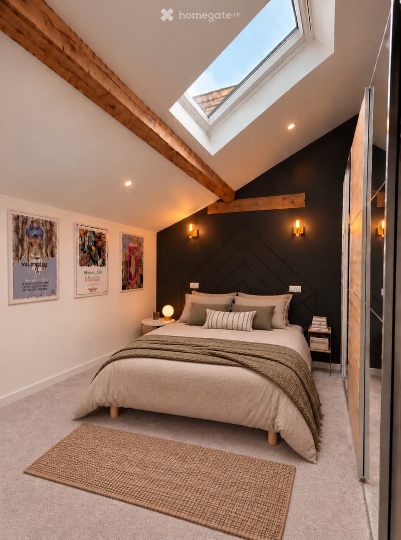 Cozy attic bedroom with exposed wooden beams, skylight window, dark accent wall, and modern decor including a bed, nightstands, and artwork.