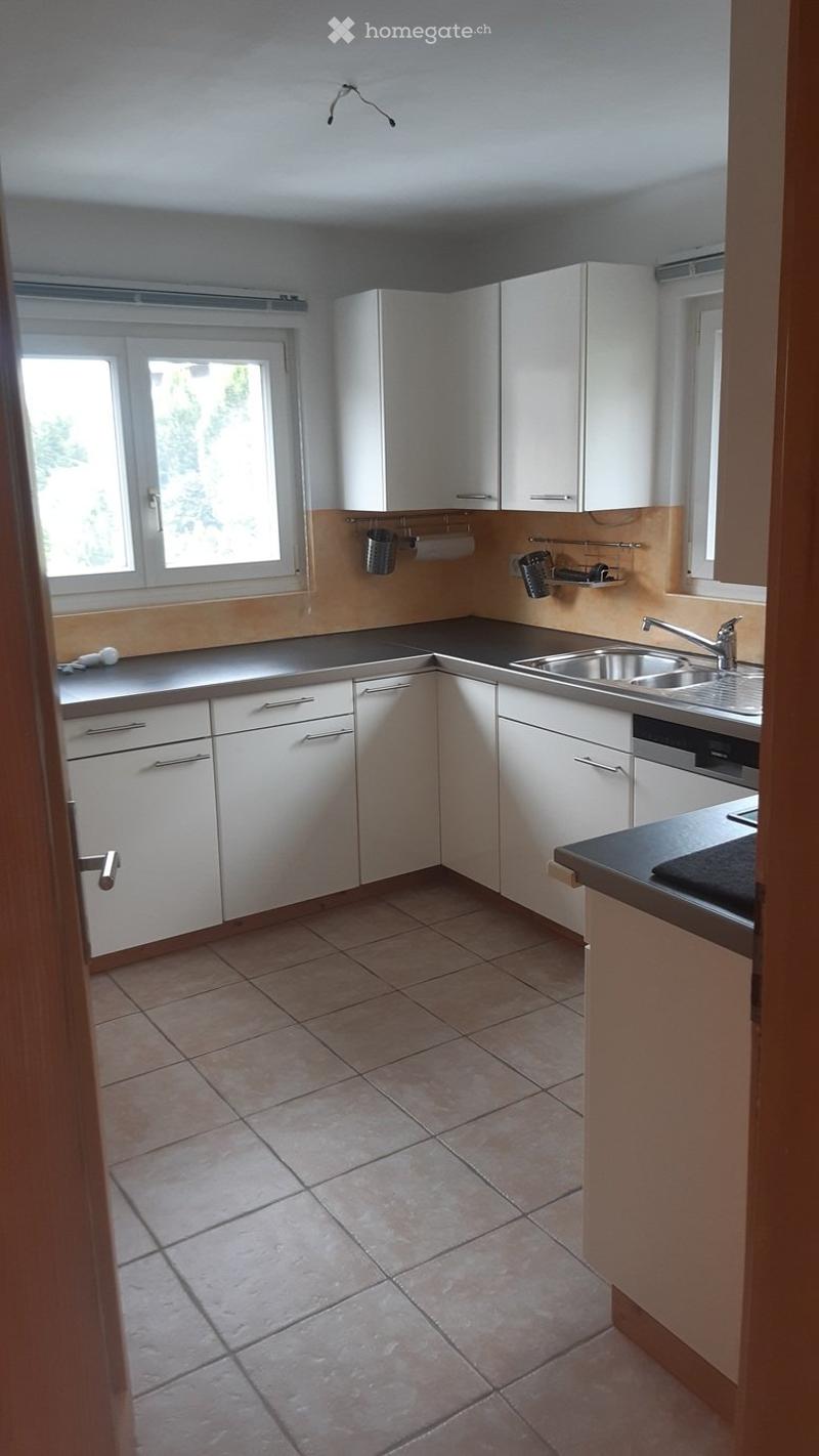 Modern kitchen with white cabinets, tiled floor, and stainless steel sink.