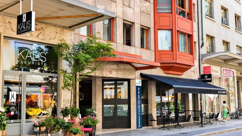 Multi-story building with storefronts including "Kalis Fleuriste" and "SushiShop" with outdoor seating area.