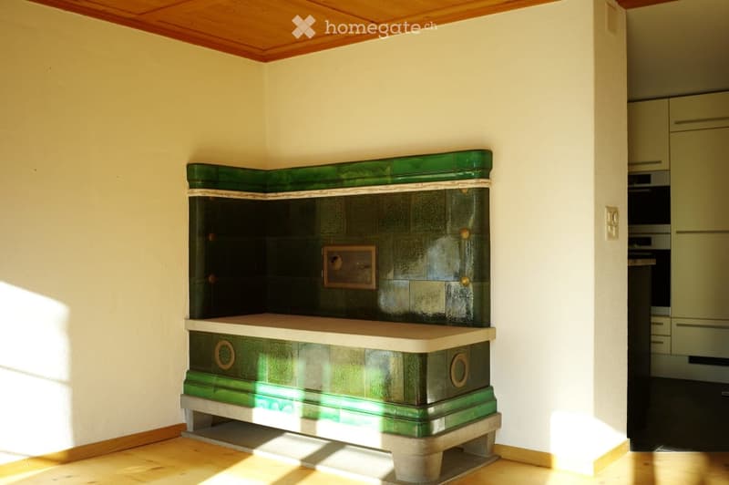A room with a green and white wooden bench, a cabinet, and an oven in the background.