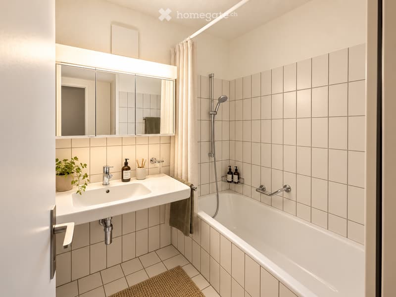 Modern bathroom with white tiles, a large mirror with built-in lighting, a double sink, a bathtub, and a small plant on the counter.