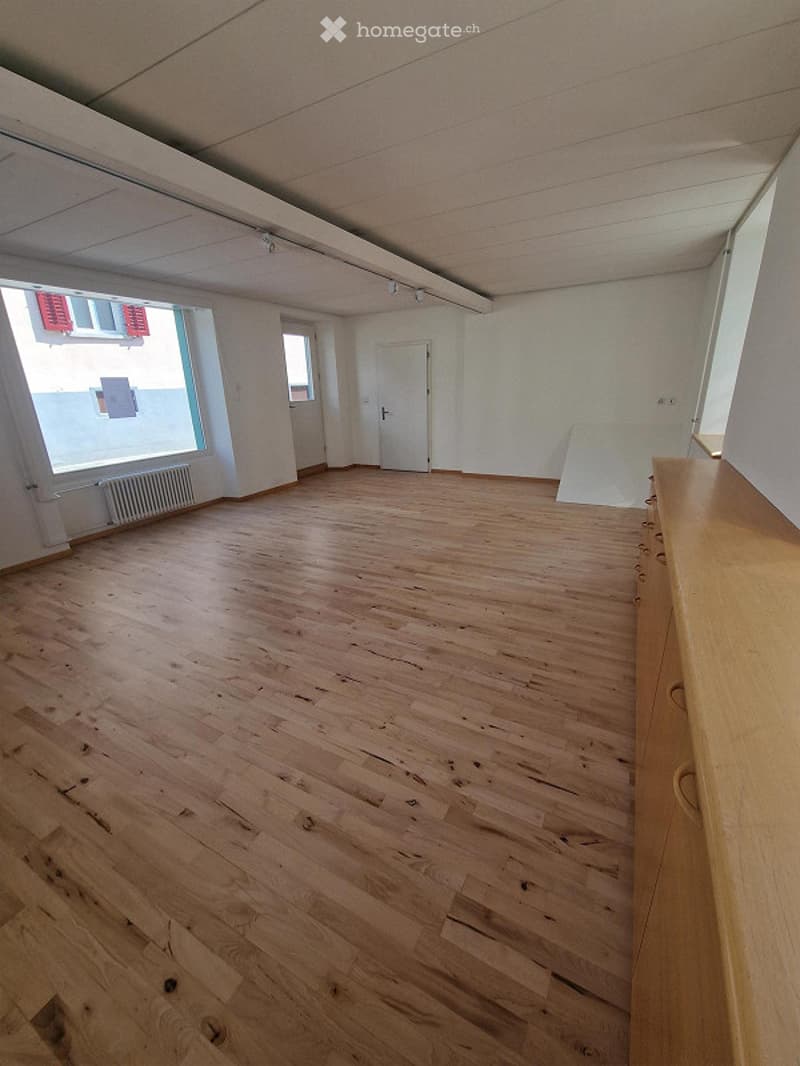 Empty room with wooden flooring, white walls, and large windows. No furniture or equipment present.