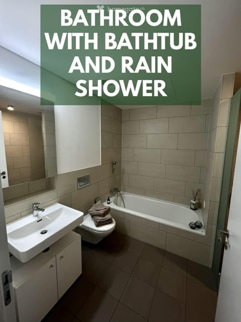 Modern bathroom with a bathtub, rain shower, sink, mirror, and toilet. Beige tiles and a clean, contemporary design.