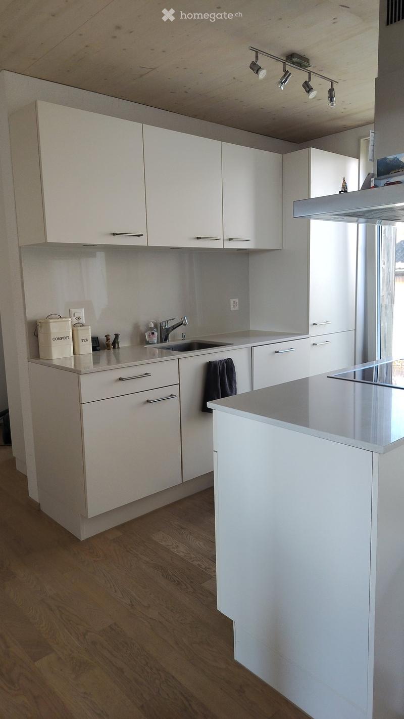 Modern kitchen with white cabinets, wooden flooring, and a central island. Features include a sink, faucet, and various storage compartments.