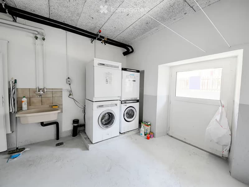A small utility room with a washing machine, dishwasher, sink, and various cleaning supplies.