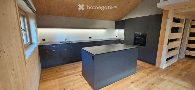 Modern kitchen with dark blue cabinets, a central island, and a sink with a faucet. The space features wooden flooring and a sleek, contemporary design.