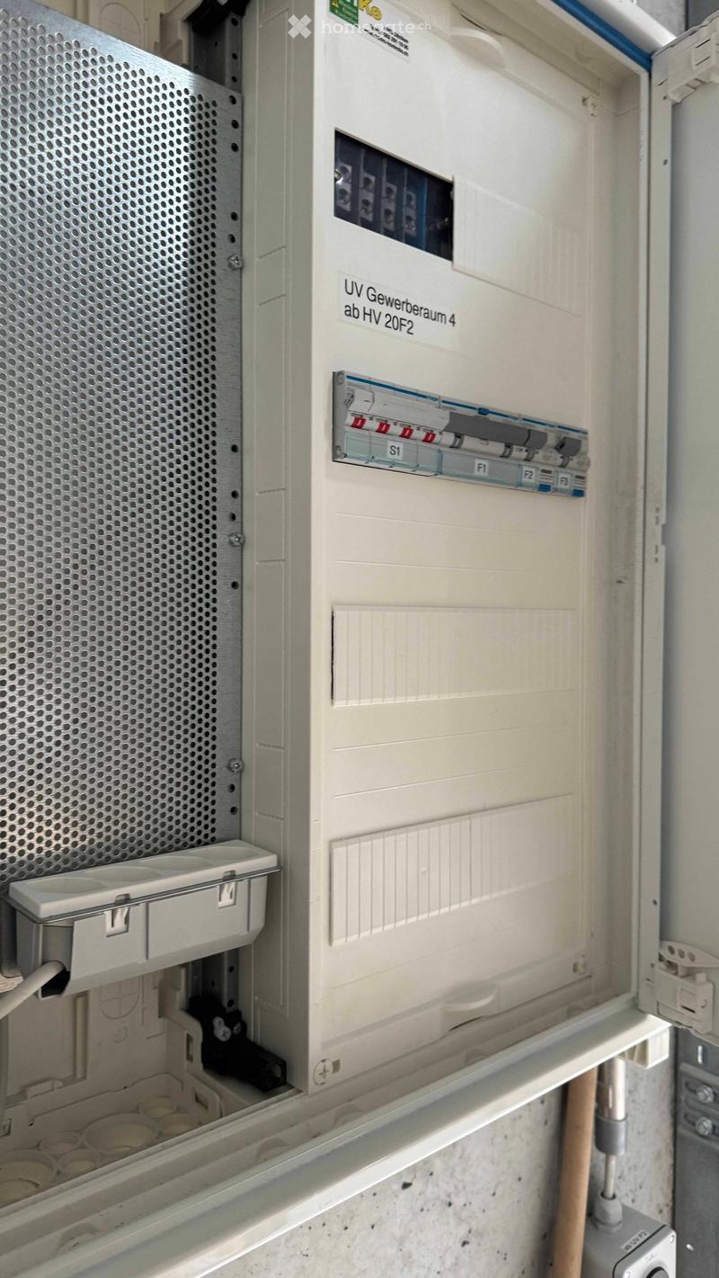 Electrical panel with circuit breakers and fuses, mounted on a wall with visible wiring and labels.