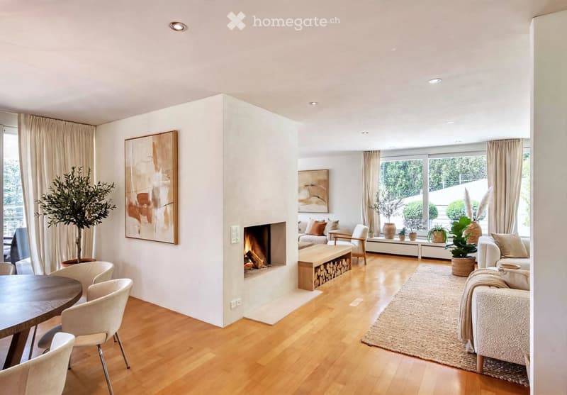 Modern living room with wooden flooring, fireplace, sofa, chairs, and artwork.