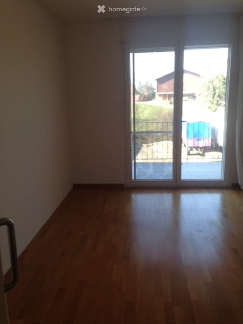 Empty room, wooden floor, glass sliding doors, balcony, white walls