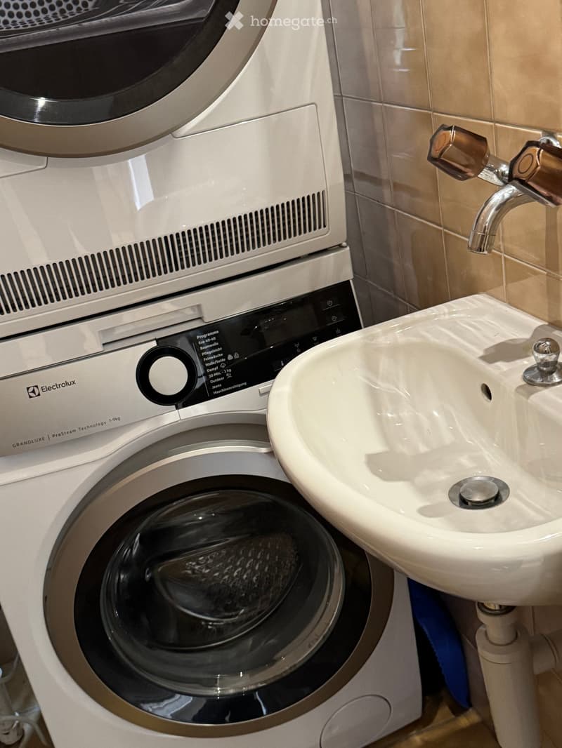 Bathroom with a white sink, chrome faucet, and a white washing machine with a control panel.