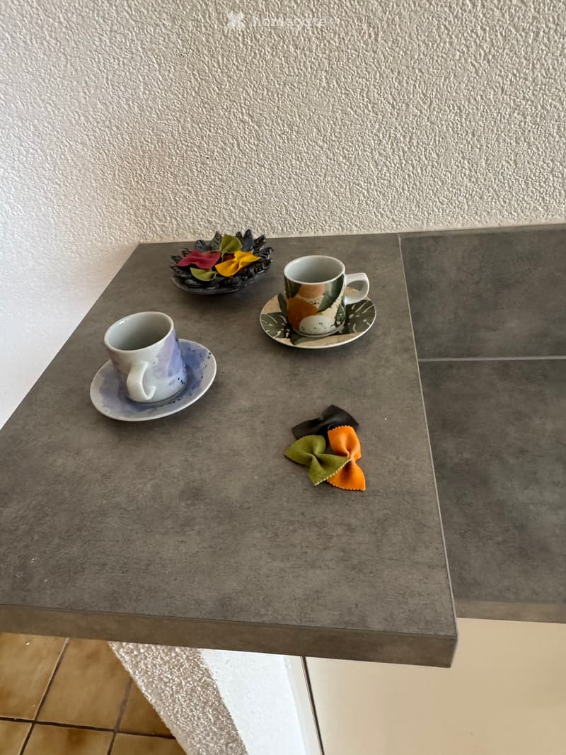 A small table with two cups on saucers, a flower arrangement, and a serving of pasta.