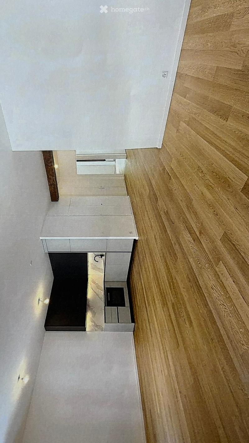 Top-down view of a modern, minimalist kitchen area with light wood flooring, white cabinetry, and a small built-in microwave. The space includes a small countertop and a staircase leading upwards.