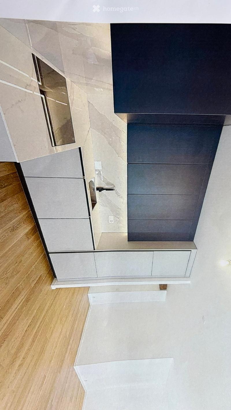 Modern kitchen with sleek, grey cabinets and a light wooden floor. The design features a minimalist aesthetic with clean lines and a neutral color palette.