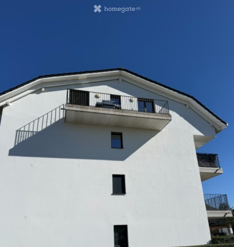 Modern two-story white building with multiple balconies and large windows.