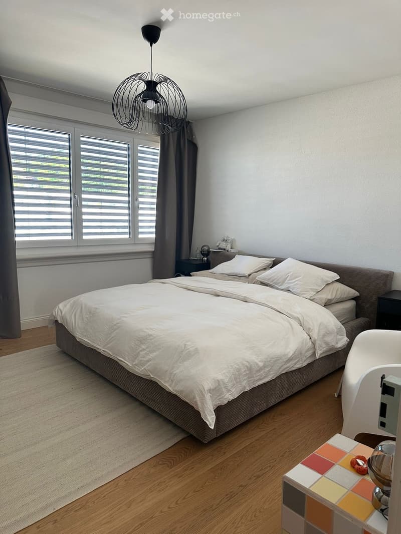 Bedroom with bed, rug, nightstands, window with blinds, and a chair