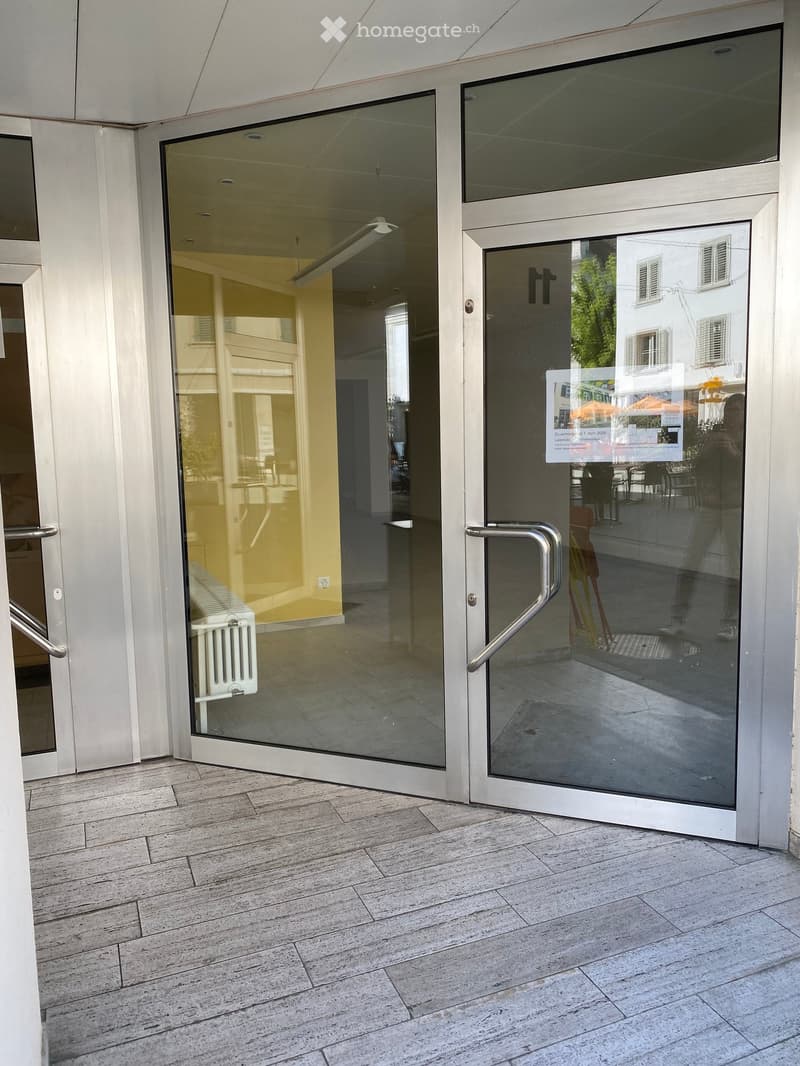 Entrance area with glass doors, tiled floor, and white walls.