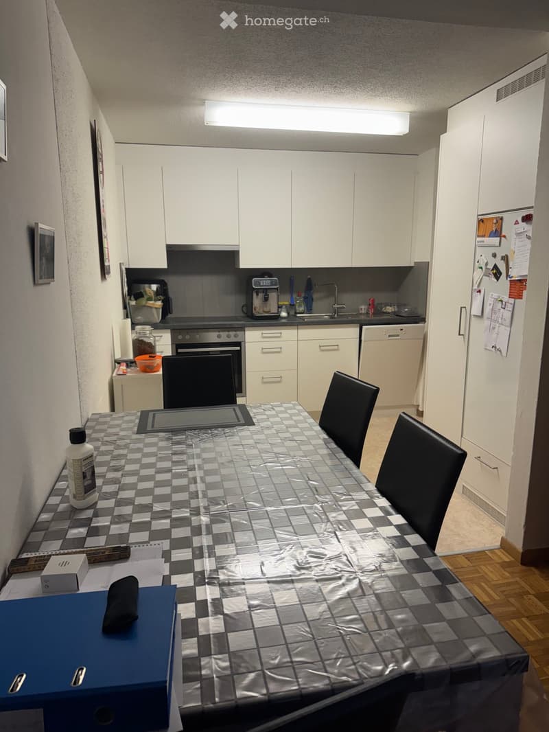 Modern kitchen with white cabinets, stainless steel appliances, and a dining area with a table and chairs.