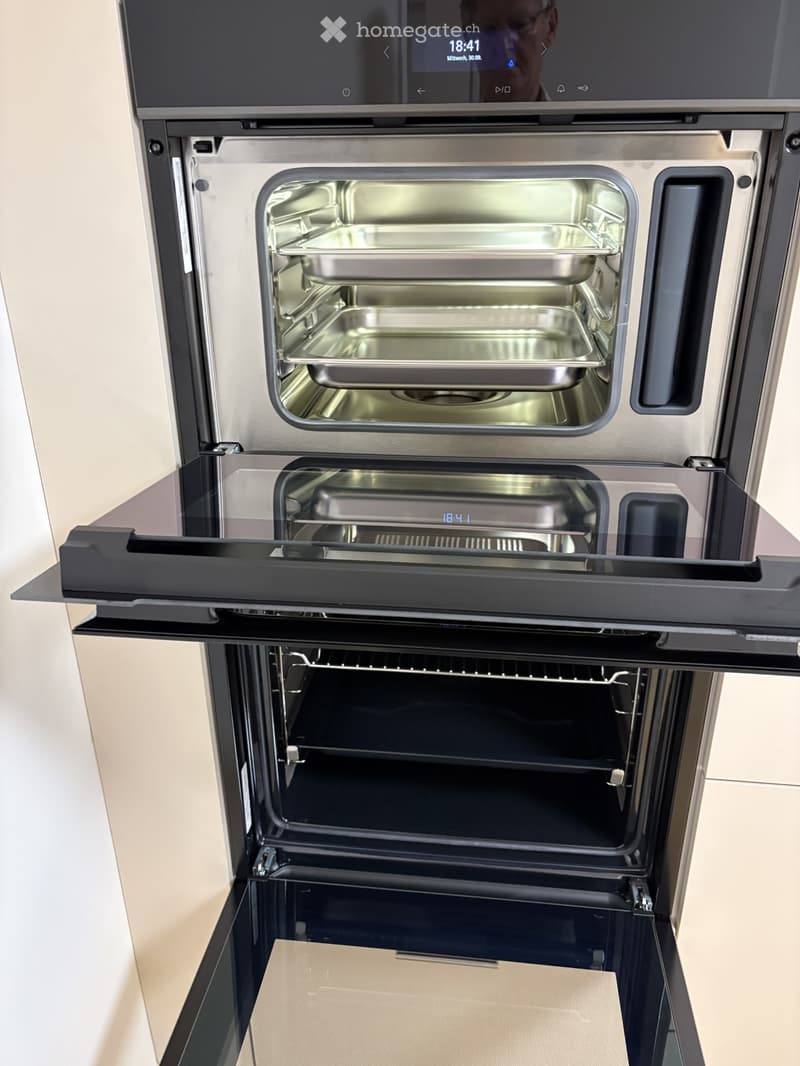 Modern stainless steel oven with multiple compartments, digital display showing time, and empty interior trays.
