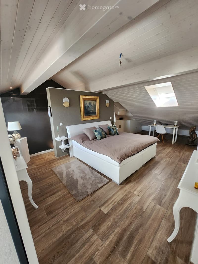 Modern bedroom with wooden flooring, white bed, nightstands, and a small desk area.
