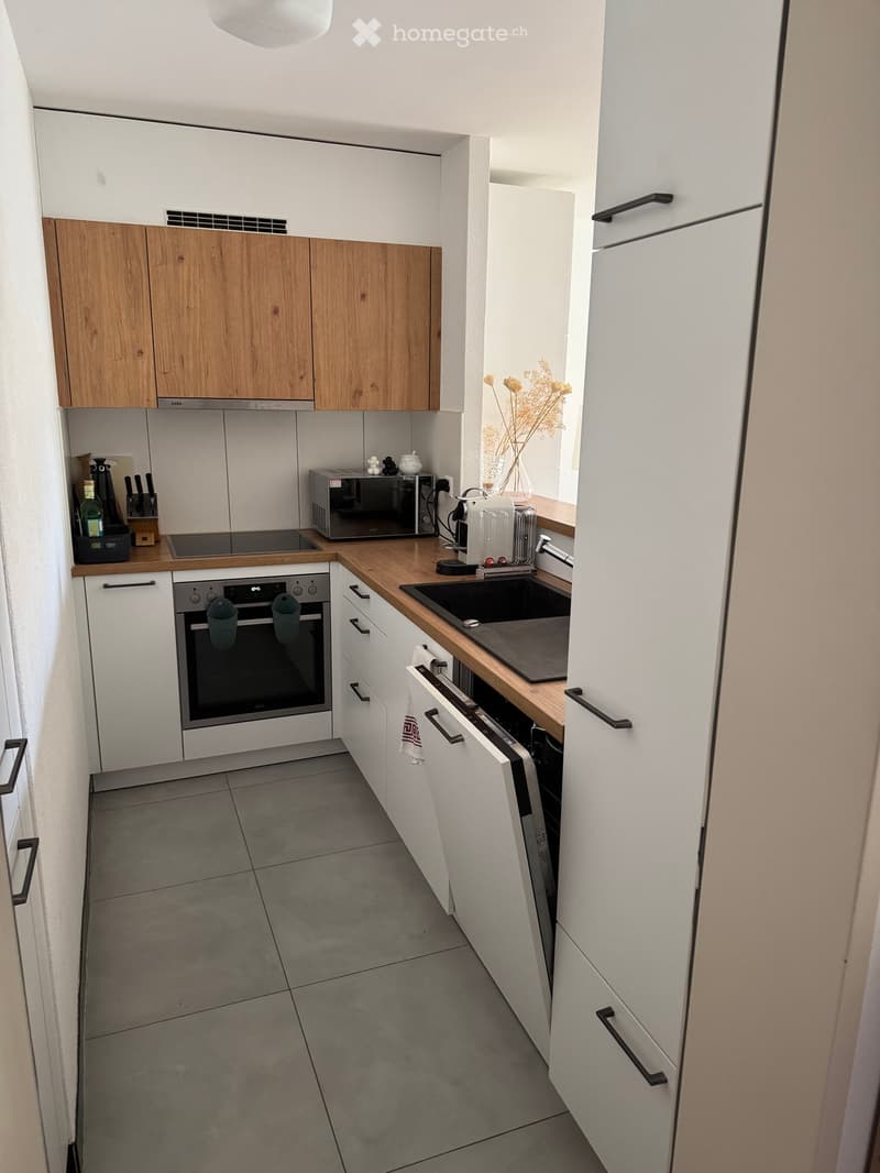 Modern kitchen with white and wooden cabinets, stainless steel appliances, and a wooden countertop.