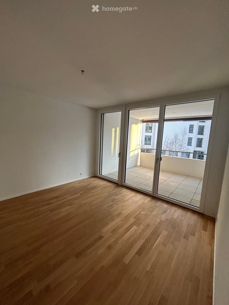 Empty room with wooden flooring and large sliding glass doors leading to a balcony.
