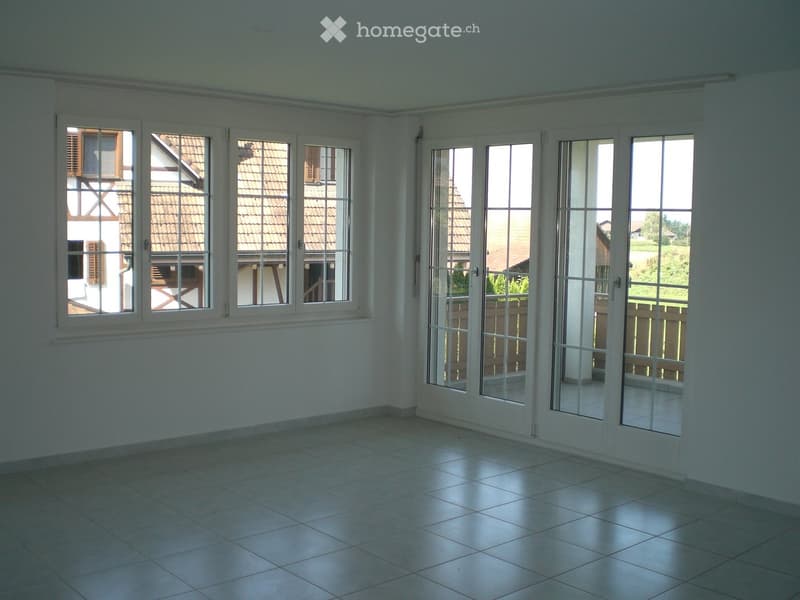 Empty room with tiled floor, large windows, and sliding glass doors leading to an outdoor area.