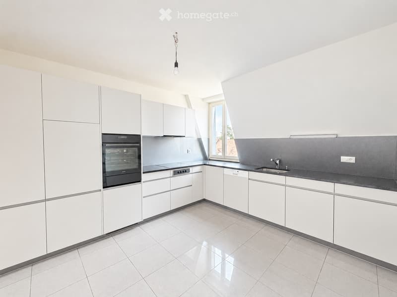 Modern kitchen with white cabinets, stainless steel appliances, and a grey backsplash. Features an oven, sink, and faucet.