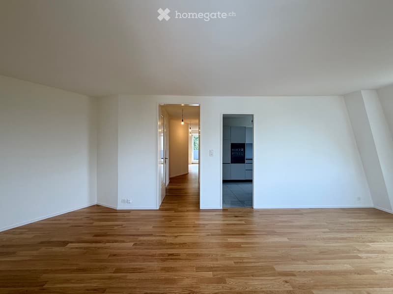 Empty room with wooden flooring and white walls, featuring two open doorways leading to other areas.