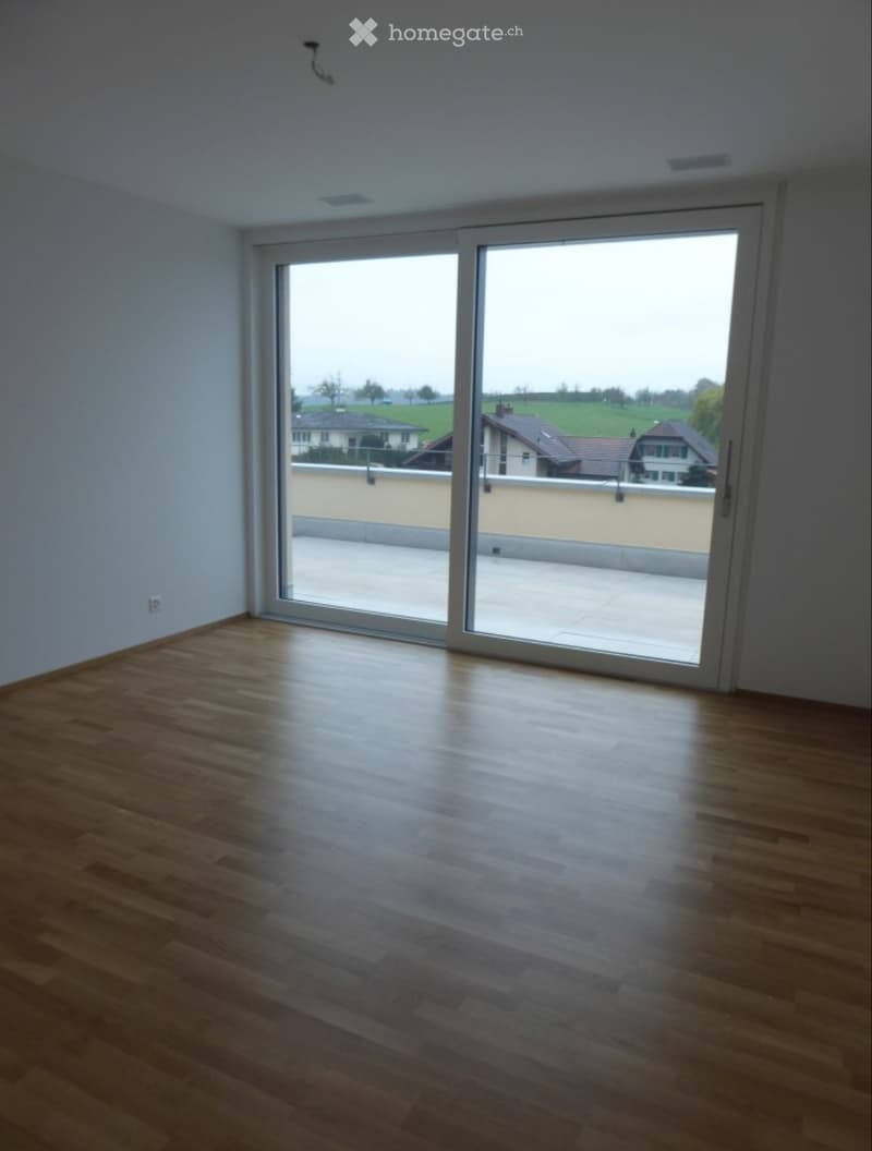 Empty room with wooden flooring and large sliding glass doors leading to a balcony or terrace.