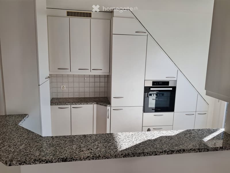 Modern kitchen with white cabinets, granite countertops, and built-in oven.