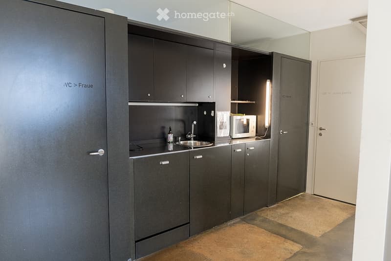 Modern kitchen with dark grey cabinets, a sink, microwave, and a small countertop area.