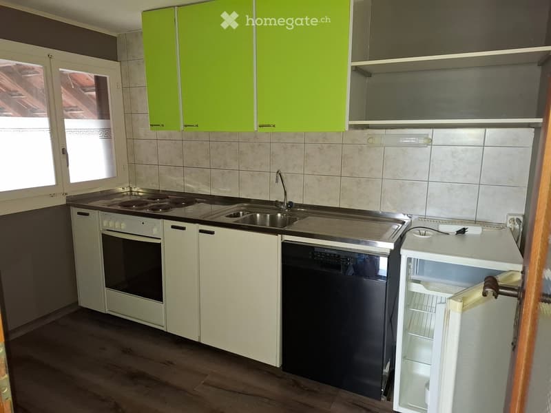 Modern kitchen with white and green cabinets, stainless steel appliances, and a window providing natural light.