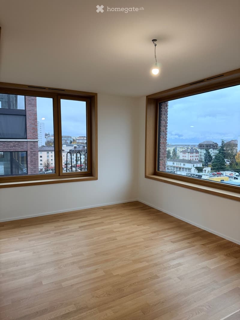 Empty room with wooden flooring, large windows, and white walls. No furniture or equipment present.