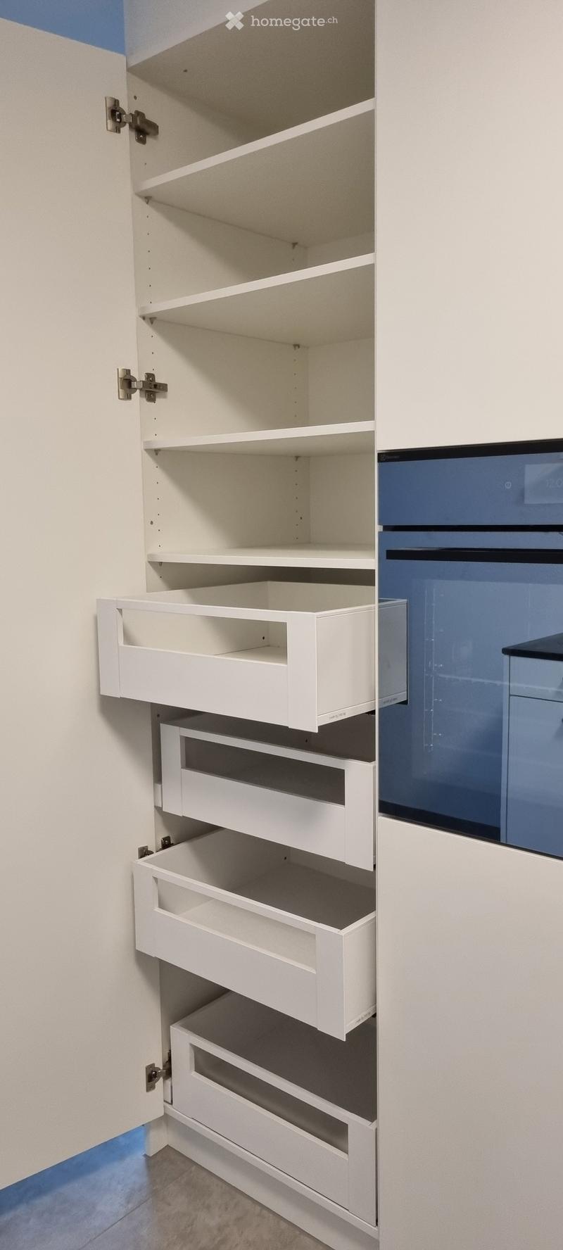White kitchen cabinet with multiple open shelves and drawers, featuring sleek design and modern hardware.
